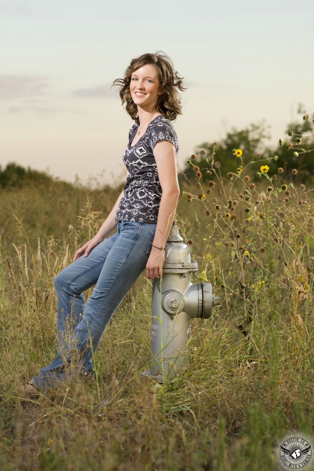 Austin senior portraits of high school senior girl reclining on a silver fire hydrant at Mueller Lake Park in Austin.