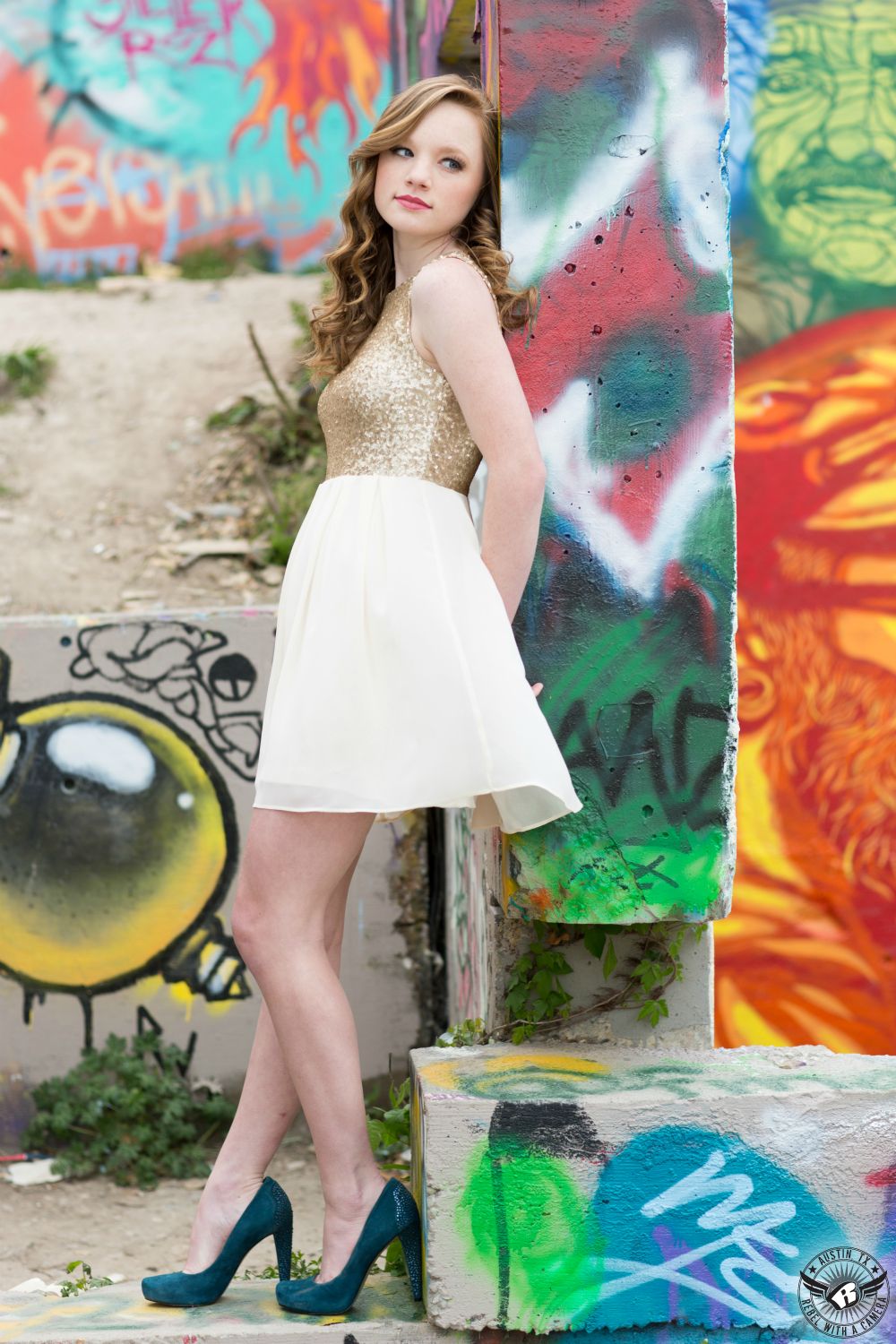 Stunning senior portrait photography of blonde girl in fancy dress with hair and makeup by Divaz Fabula at the Castle Hill Graffiti wall in Austin, Texas.