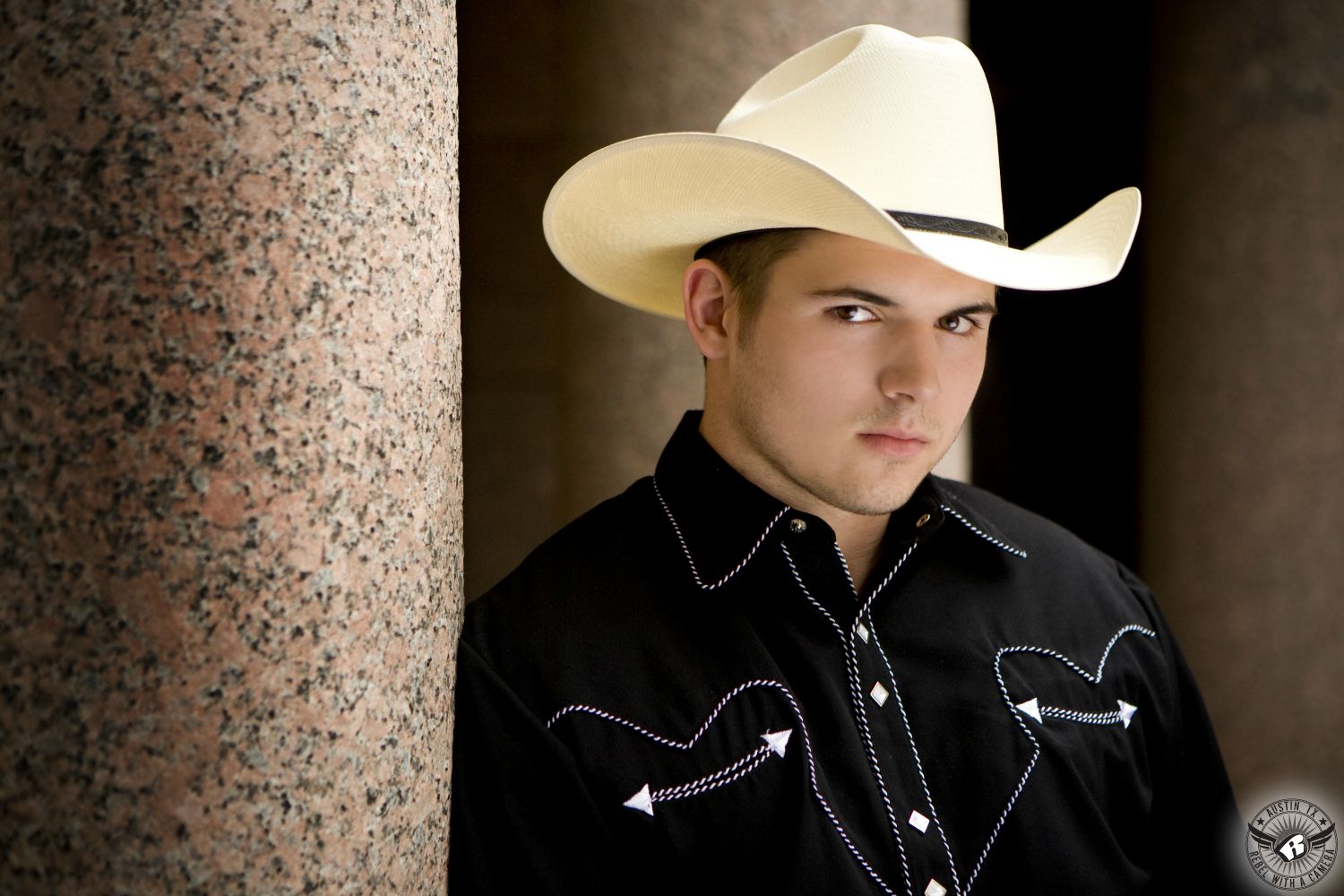 Very serious image of high school senior boy in cowboy hat and western shirt taken at the Texas State Capitol in Austin taken by the best senior portrait photographer.