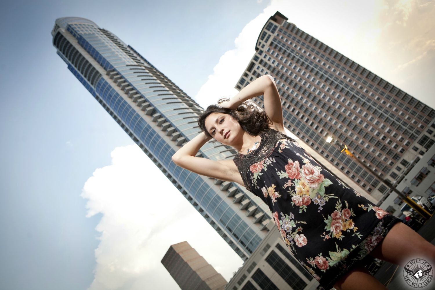 High school senior portraits Austin in downtown of girl in cute, black flowered dress with high rise buildings.