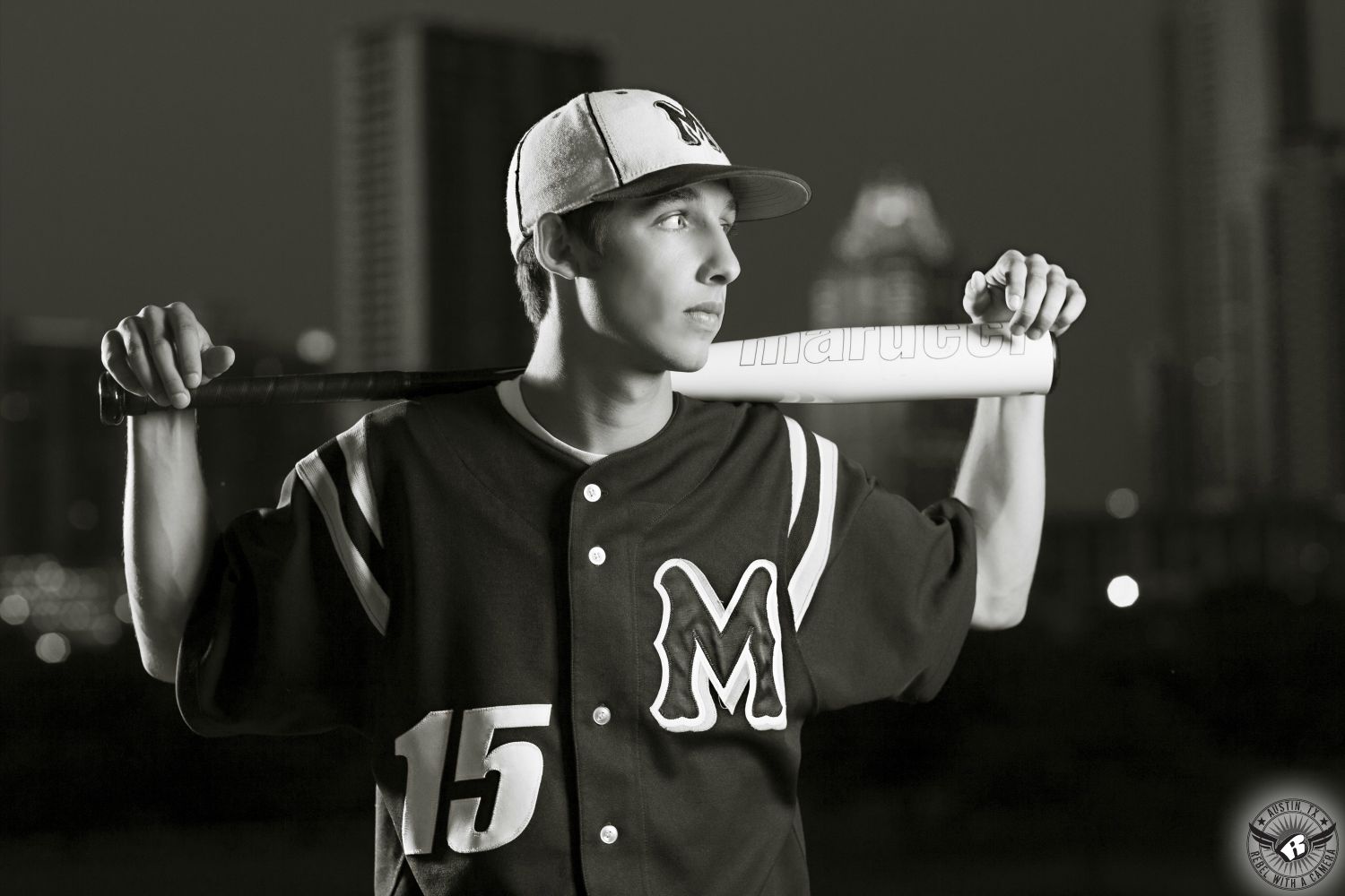 Austin senior portraits at the Long Center of high school athlete with baseball bat and jersey with the Austin skyline behind.