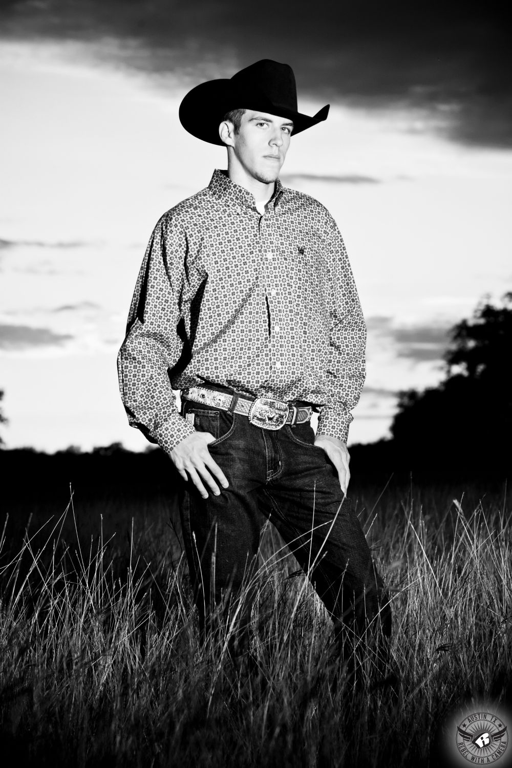 Country senior portrait photography of boy in cowboy hat and jeans taken on ranch in Central Texas.