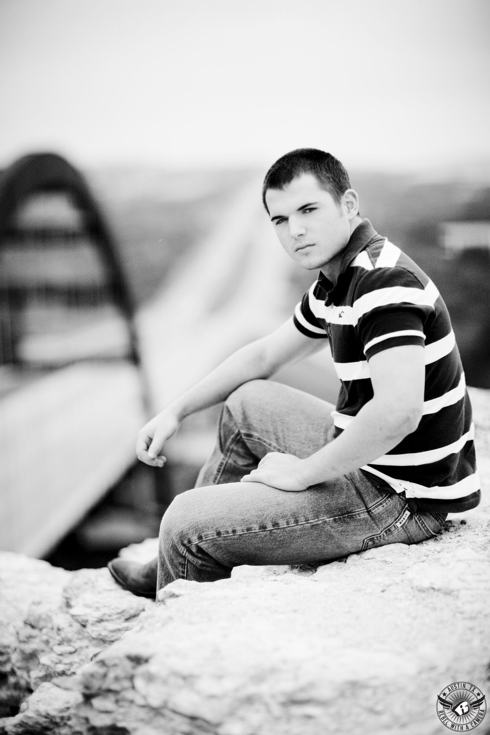 Pennybacker Bridge in Austin high school senior pictures of young man in jeans and striped shirt.