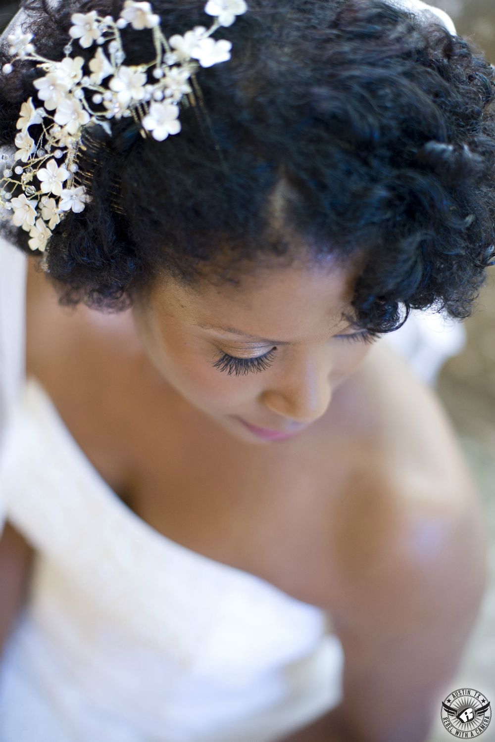 Veautiful African American bride in white strapless bridal gown looking down at her shoulder in bridal room in Nature's Point Austin wedding venue on the shores of Lake Travis.