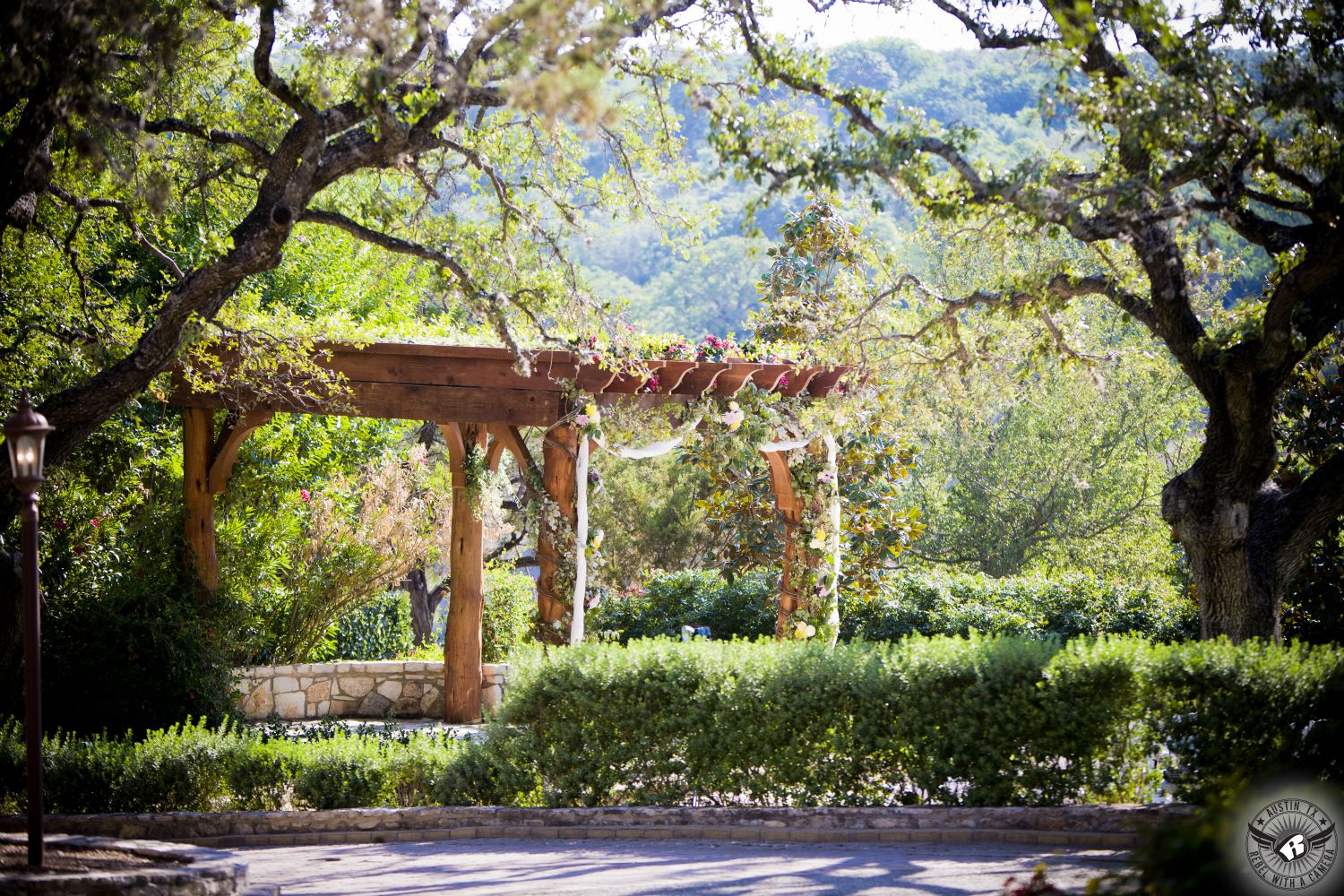 Beautiful arbor covered with flowers at outdoor wedding ceremony site surrounded by towering oak trees at Nature's Point Austin wedding venue on the shores of Lake Travis.