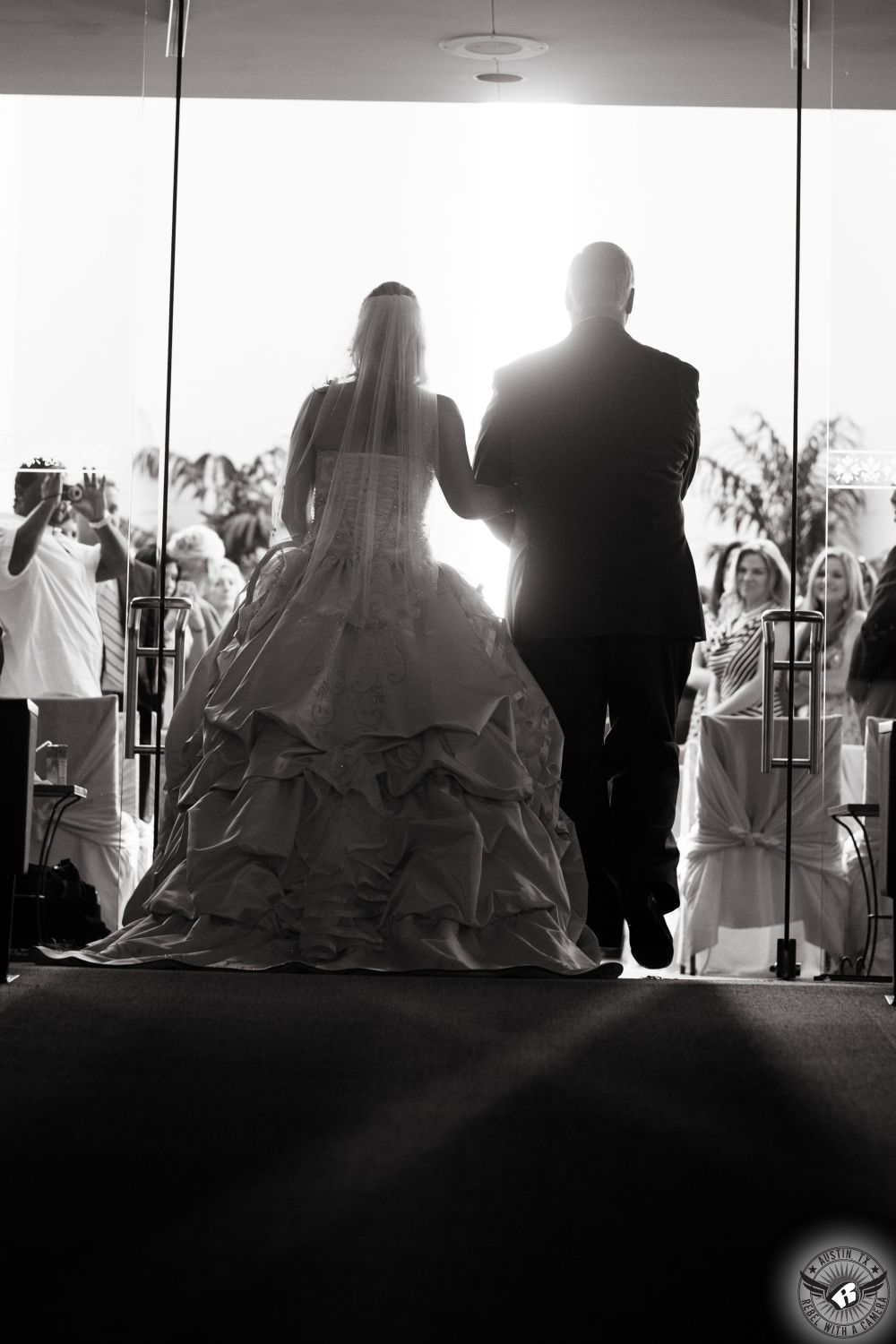 Dramatic black and white image of bride in gorgeous wedding ball gown being walked down the aisle by father at Unity Church in Houston, Texas.