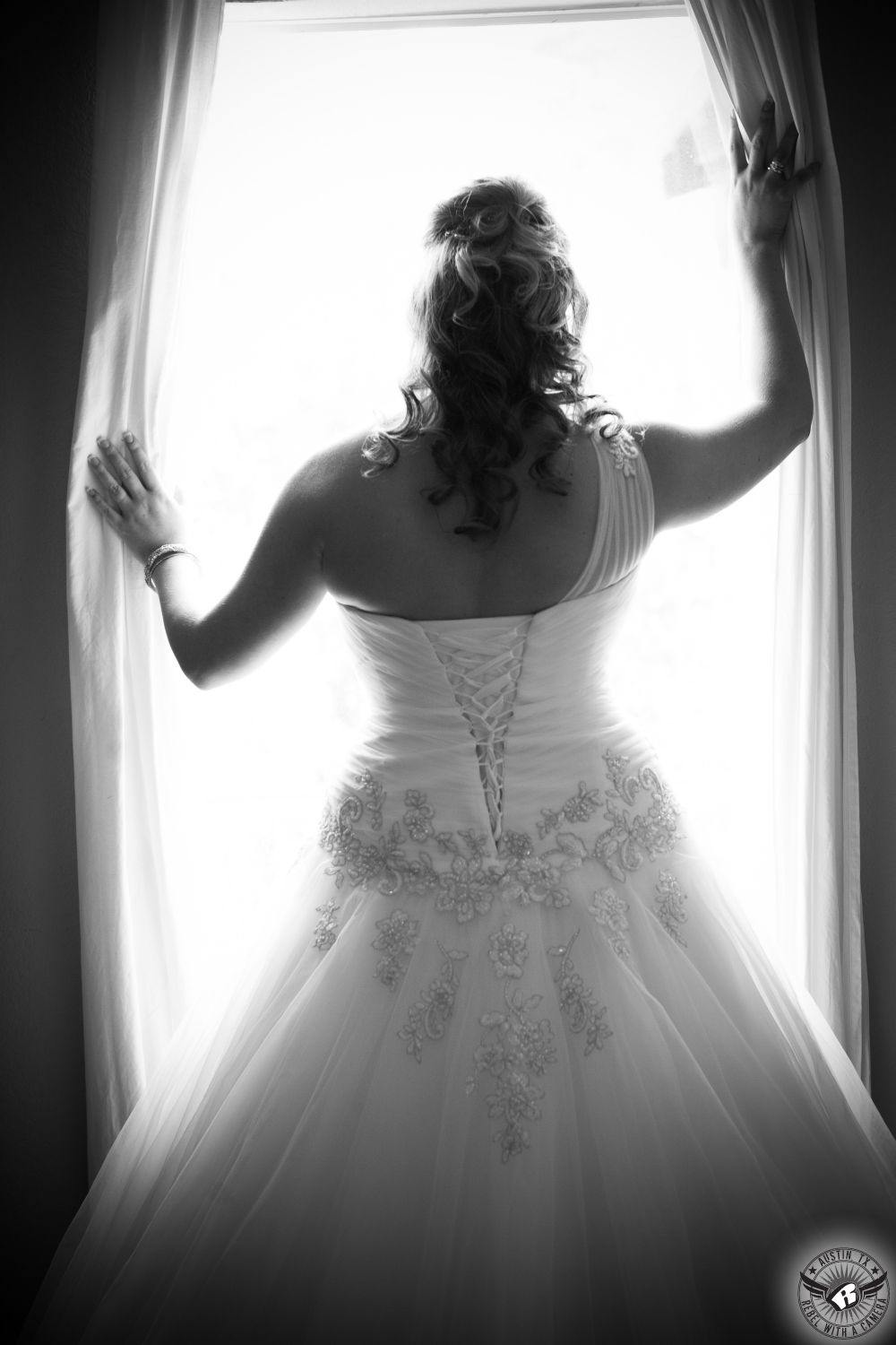 Stunning black and white wedding picture of bride from the back in front of a window at Kali-Kate Austin area wedding venue taken by Austin wedding photorapher.