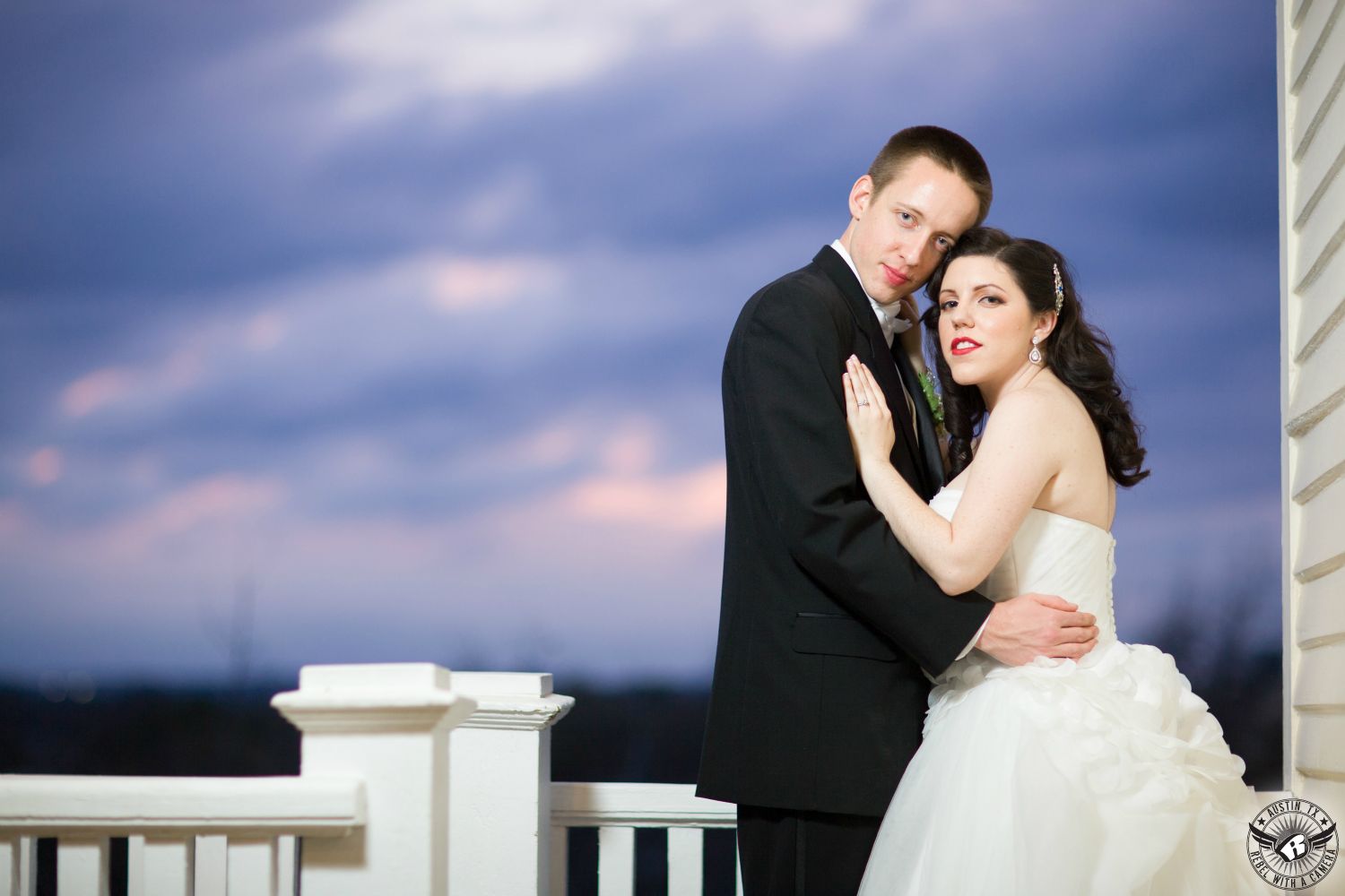 Photo of bride in White bridal gown by Vera Wang from David's Bridal and groom in black tuxedo in front of dramatic sky off the balcony at the Allan House downtown Austin wedding venue taken by Austin wedding photographer.
