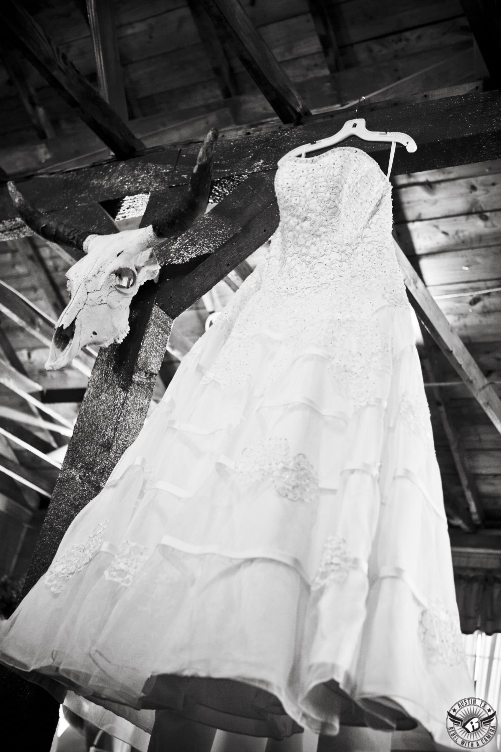 Wedding picture of bride's wedding dress hanging up in bridal room next to cow skull at the Cotten Club in Granger, Texas, taken by Austin wedding photographer.