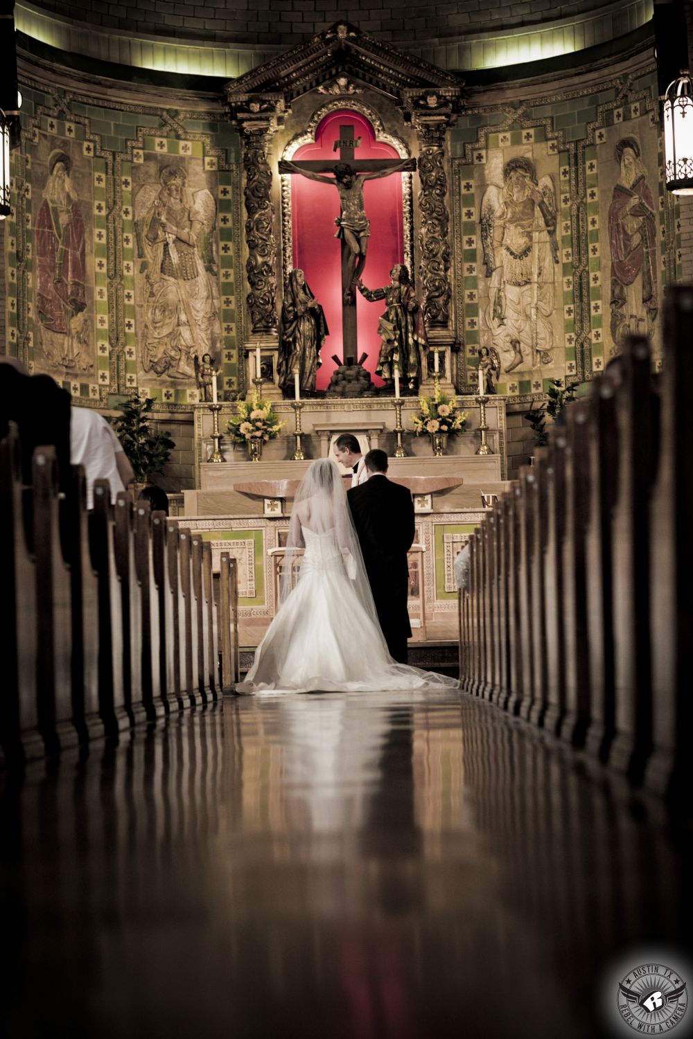 Dramatic image of bride and groom at the altar of cathedral during Catholic wedding ceremony taken by Austin wedding photographer.