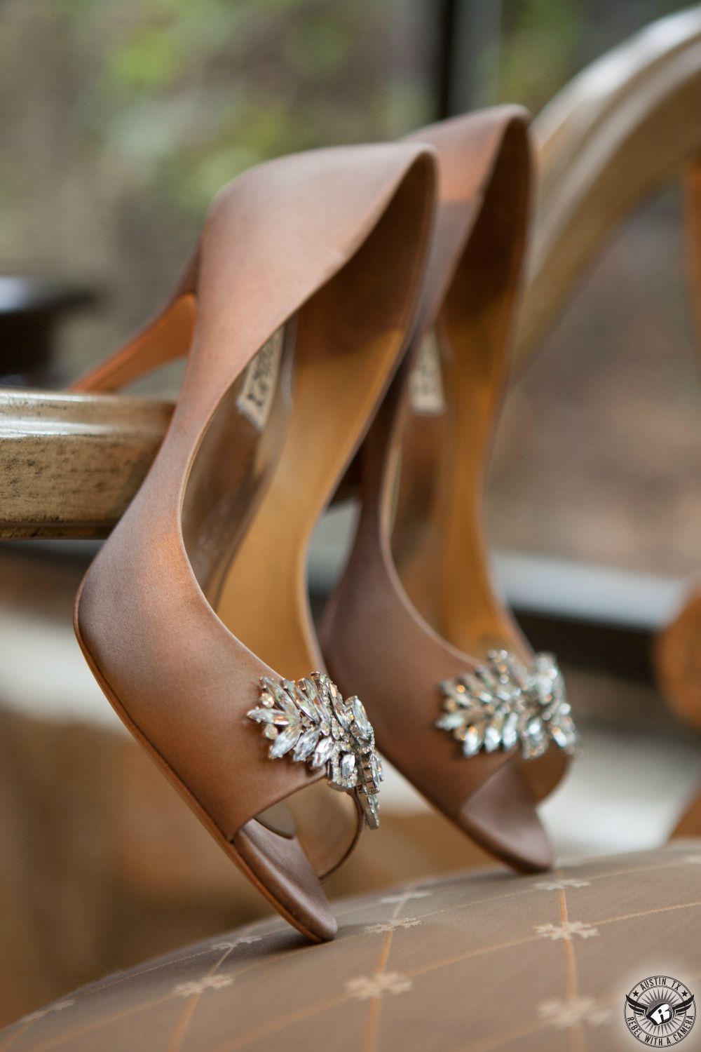 Wedding picture of delicate mauve silk shoes with diamond embellishments on fancy chair in bridal room at the Austin wedding venue Nature's Point on the shores of Lake Travis taken by Austin wedding photographer Rebel with a Camera.
