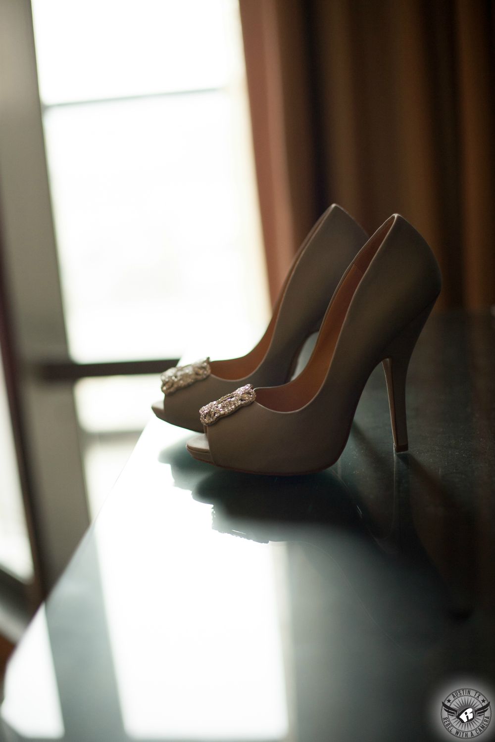 Artistic shot of grey high heels with diamond clasp for the bride in the window light in a bridal suite at the Omni Austin downtown taken by Rebel with a Camera, Austin wedding photographer.