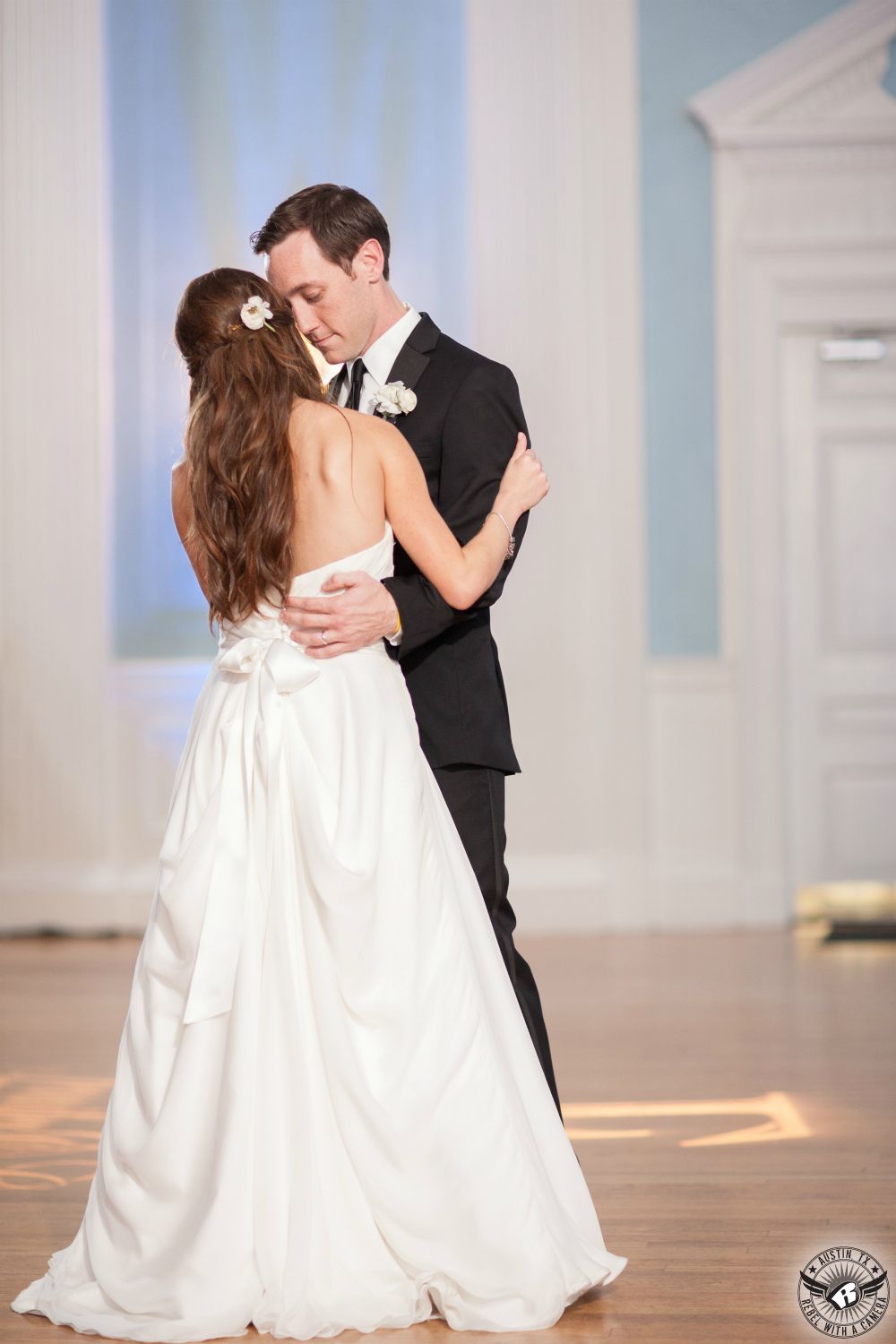 Austin wedding photography of first dance of bride in strapless wedding gown and groom in black tuxedo in the light blue ballroom at the Texas Federation of Women's Clubs Mansion Headquarters with the Rocket Brothers Band playing coordinated by Clearly Classy Events Austin wedding planner.