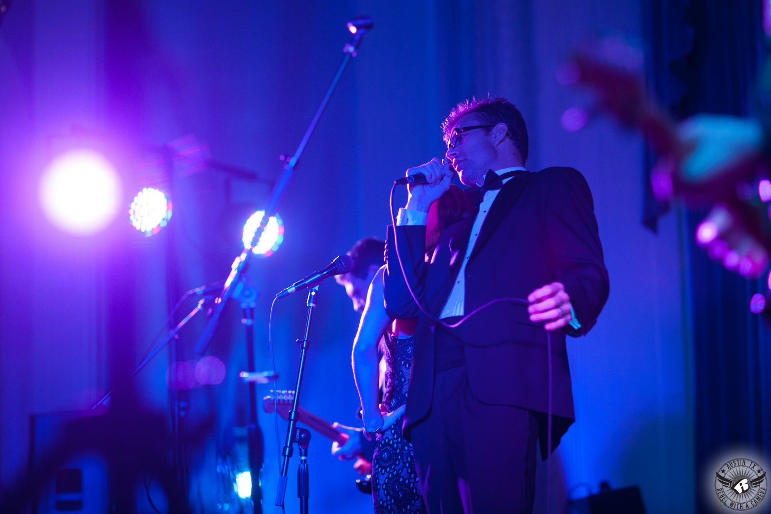 Dynamic shot of the lead singer of the Rocket Brothers Band playing at a wedding on stage at Texas Federation of Women's Clubs Mansion Headquarters with stunning blue and purple uplighting by  D&H Stage Lighting coordinated by Clearly Classy Events Austin wedding planner