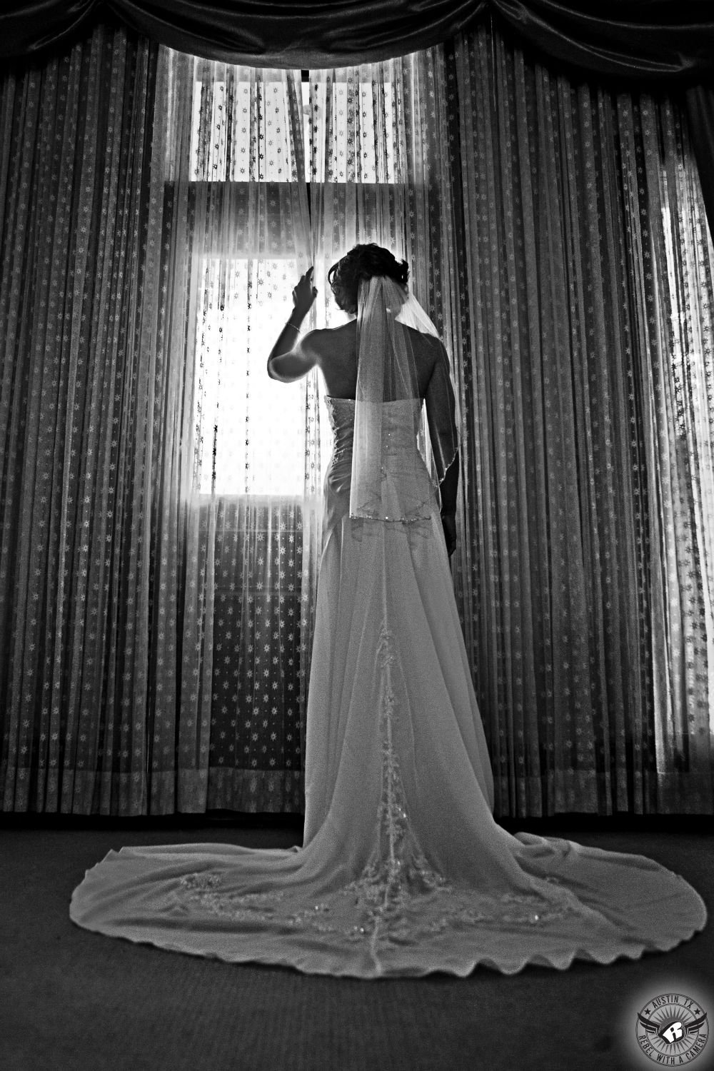 Dramatic black and white image of bride in strapless wedding dress looking out the window of Green Pastures.