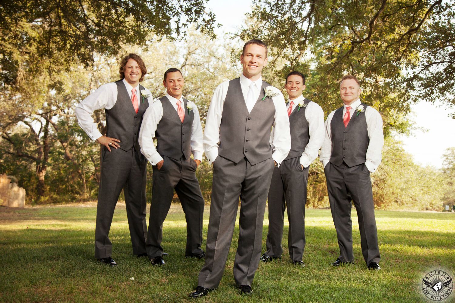 Great picture of happy groom and groomsmen in grey suit pants and vests with pink ties and white boutonnieres from Zuzu's Petals at Kindred Oaks wedding venue in Central Texas taken by Austin wedding photographer.