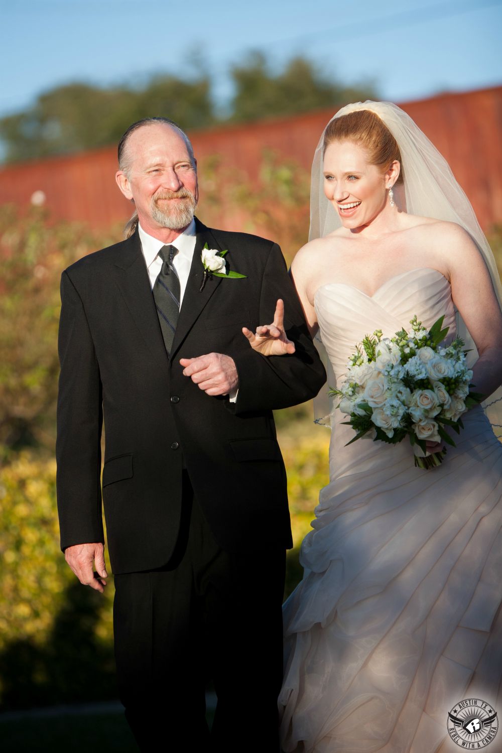 Father of the bride who carries luscious white bridal bouquet from Verbena Floral Design Austin wedding florist walks her down the aisle at Vintage Villas wedding venue in Austin on Lake Travis.