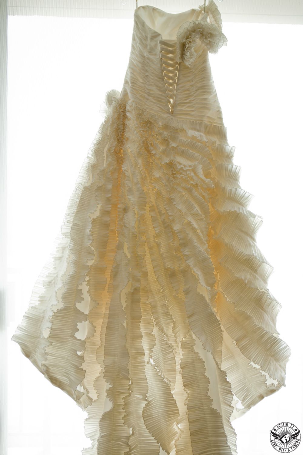 Picture of amazing ruffled wedding wedding dress hanging in the window in bridal suite at the Galleria Westin in Houston taken by Rebel with a Camera.