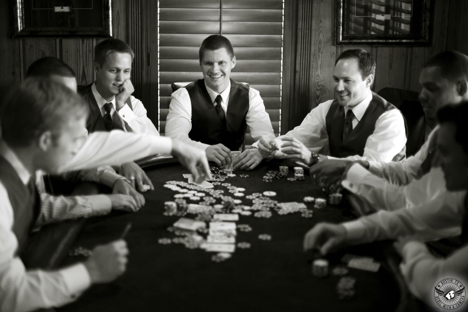 Austin wedding photographer takes picture of groom and groomsmen in black vests playing poker in the groom's cottage at Nature's Point, wedding venue in Austin.