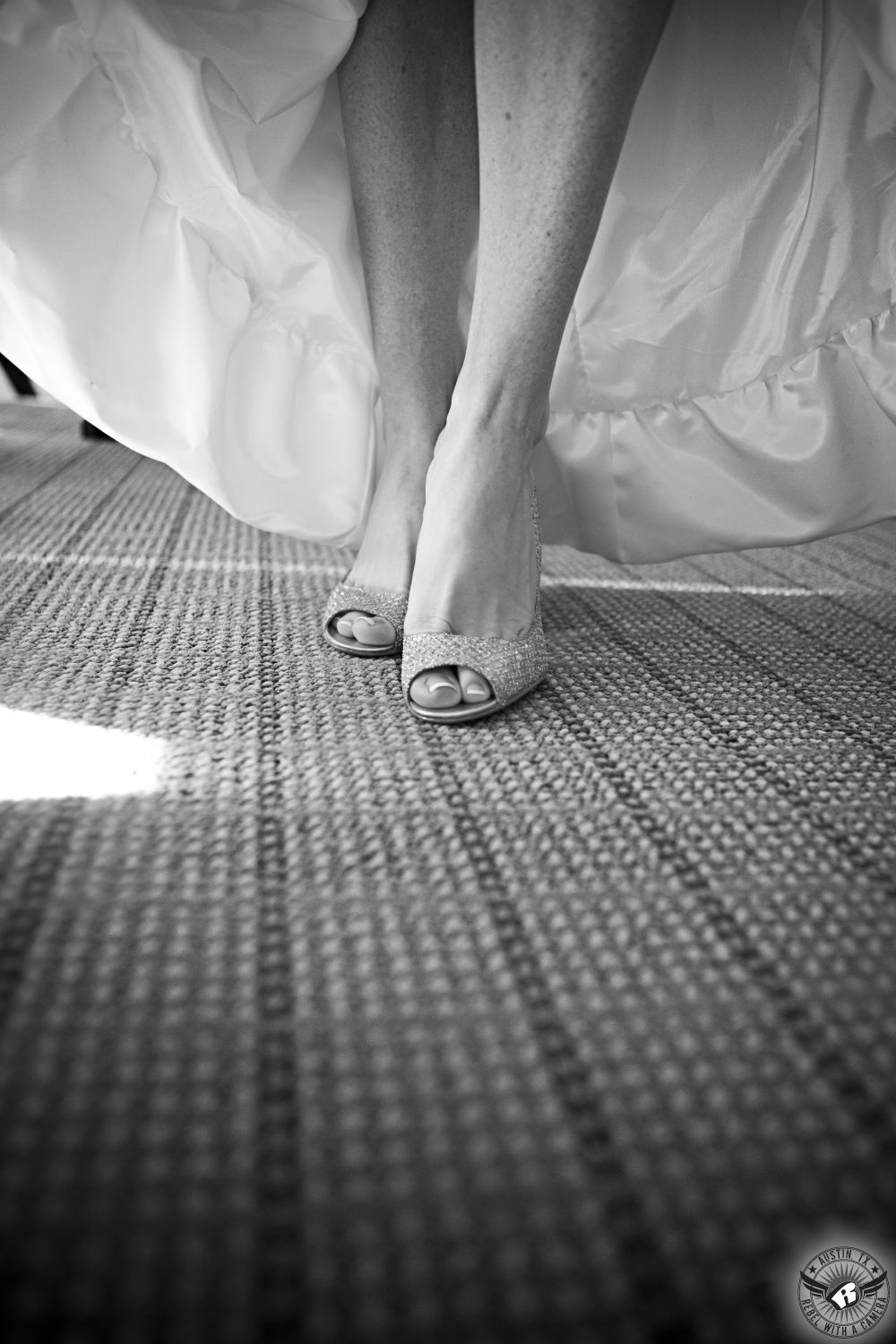 Black and white artistic detail shot of bride's shoes under her dress in the bride's room on the wedding day.