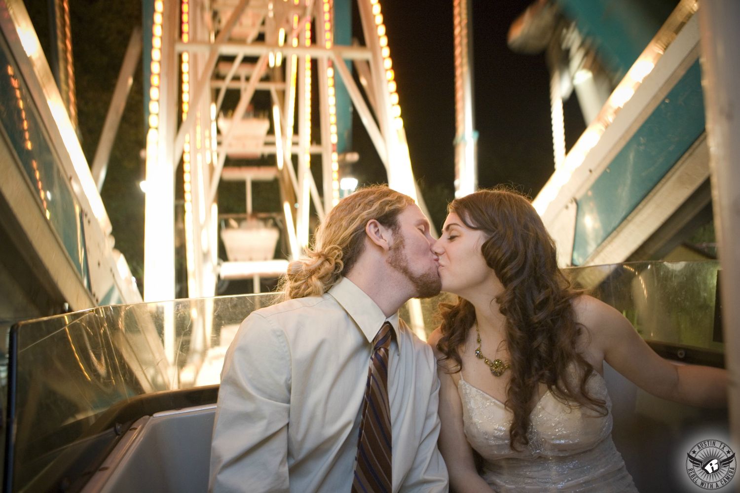 Austin wedding photography of  bride with long, dark hair and groom with red ponytail kissing on a ferris wheel at the end of their wedding in Austin.