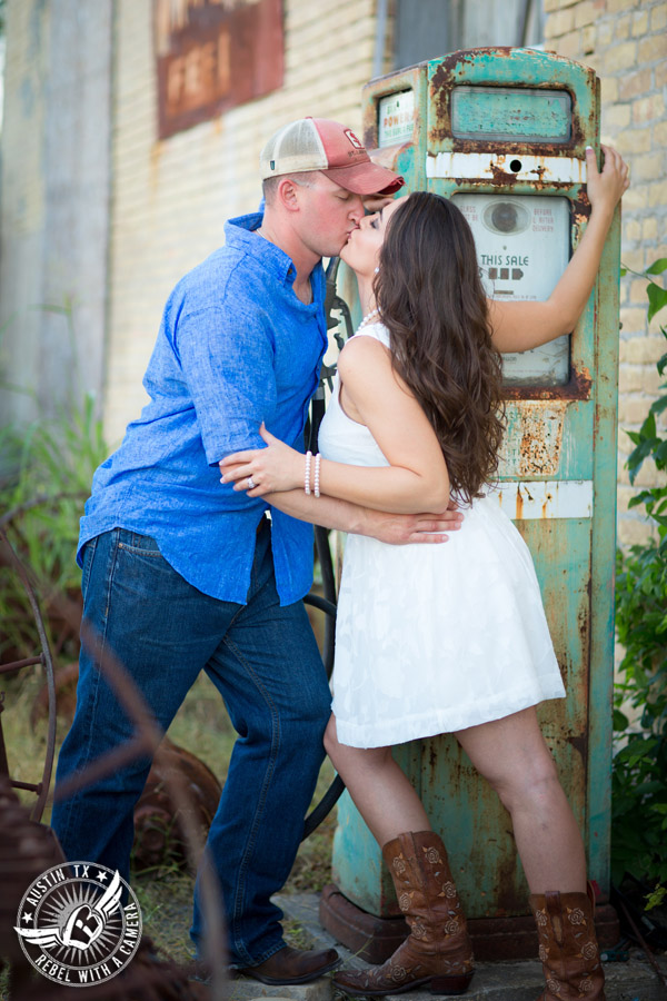 Army engagement session in Texas bride and groom kiss with old gas pump in rustic country town