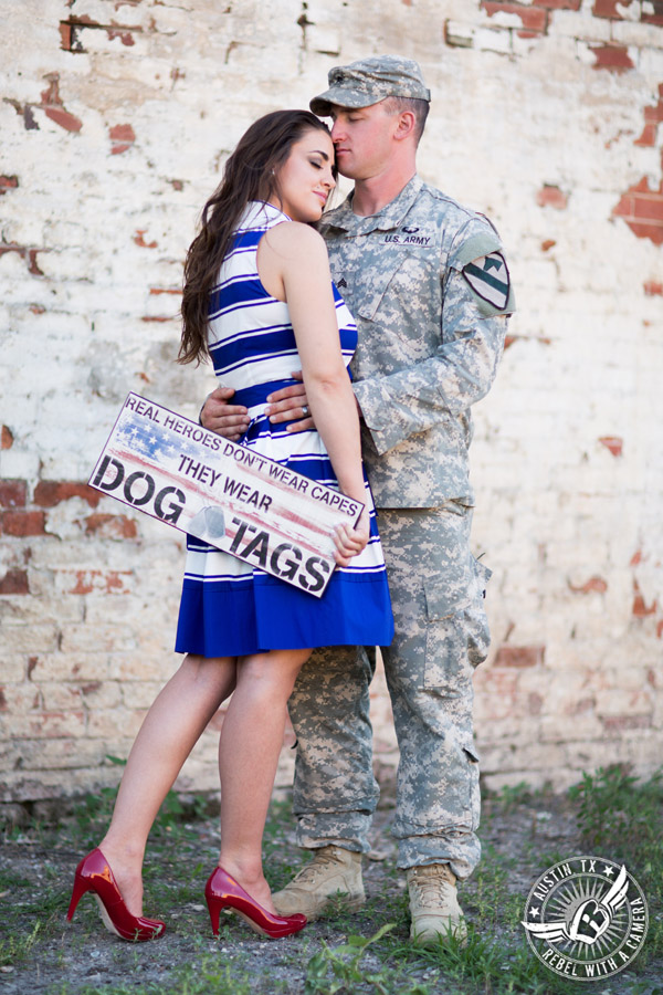 Army engagement pictures in Texas soldier and bride embrace in front of brick wall