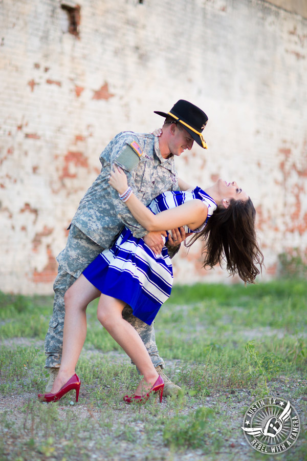 Army engagement pictures in Texas soldier dips bride in front of brick wall