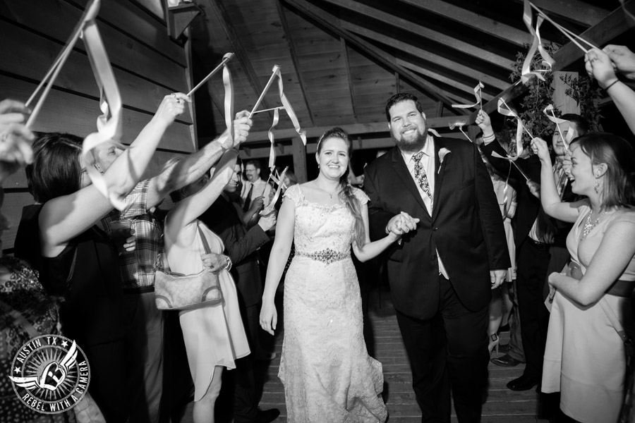 Sage Hall wedding photos at Texas Old Town happy bride and groom exit the reception while guests wave ribbon wands