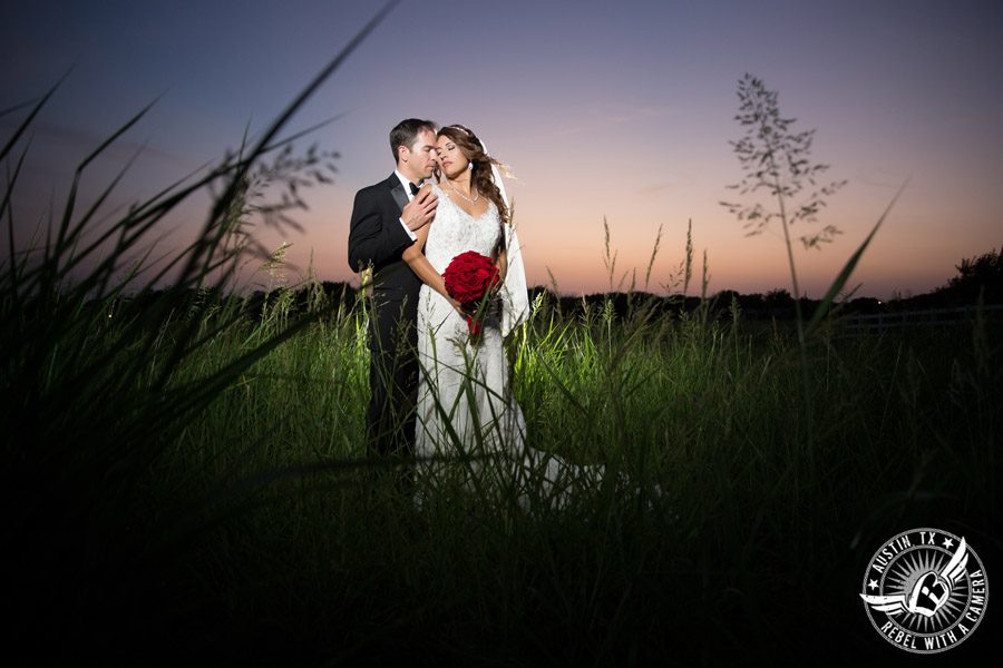 Taylor Mansion wedding photo of bride and groom in field at sunset with red rose bouquet