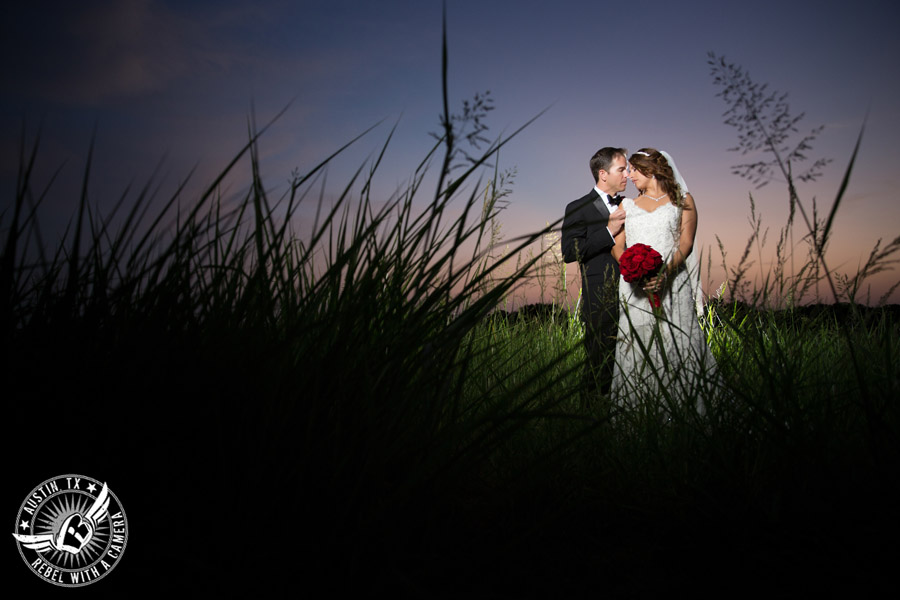 Taylor Mansion wedding photo of bride and groom in field at sunset with red rose bouquet