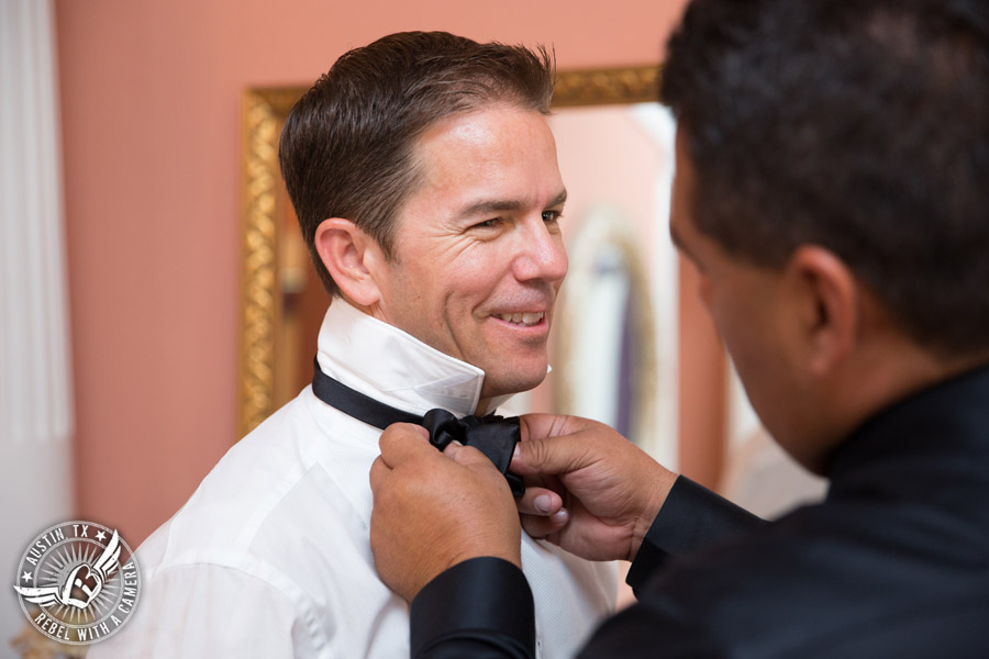 Taylor Mansion wedding photo groomsman ties bowtie for groom in groom's room