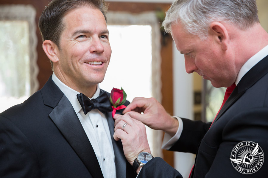 Taylor Mansion wedding photo groomsman pins boutonniere on groom in groom's room