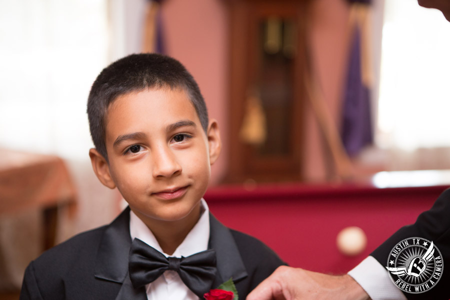 Taylor Mansion wedding photo groom pins boutonniere on ring bearer in groom's room