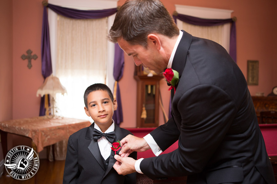 Taylor Mansion wedding photo groom pins boutonniere on ring bearer in groom's room