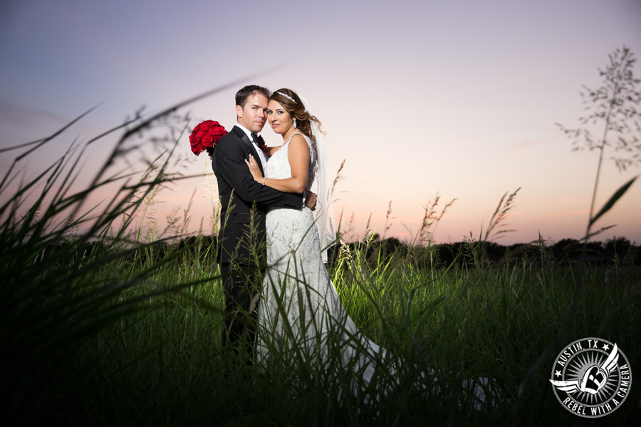 Taylor Mansion wedding photo of bride and groom in field at sunset with red rose bouquet