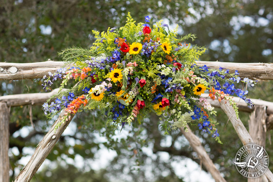 Wedding pictures at Thurman's Mansion at the Salt Lick - colorful wildflower arbor at the ceremony site by Verbena Floral Design