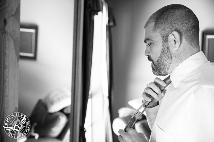 Wedding pictures at Thurman's Mansion at the Salt Lick - groom puts on tie in the groom's room