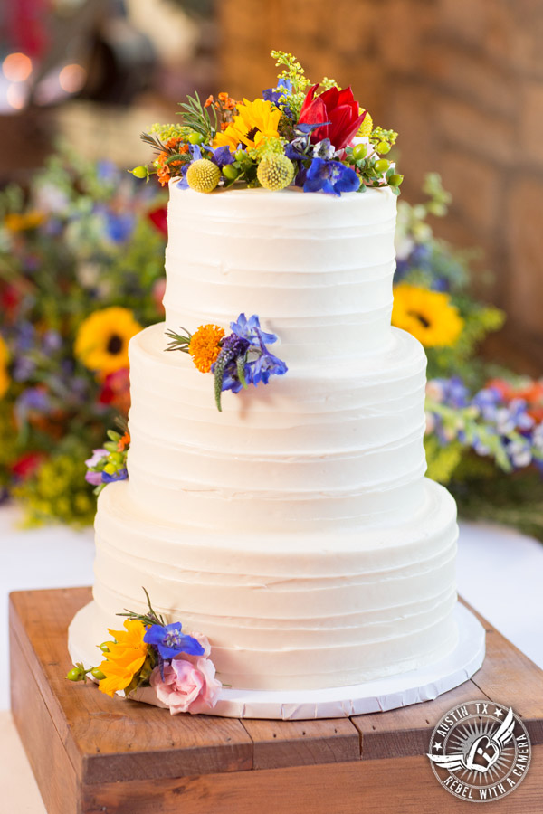 Wedding pictures at Thurman's Mansion at the Salt Lick - white buttercream bride's wedding cake Sweet Treets Bakery with colorful wildflowers by Verbena Floral Design