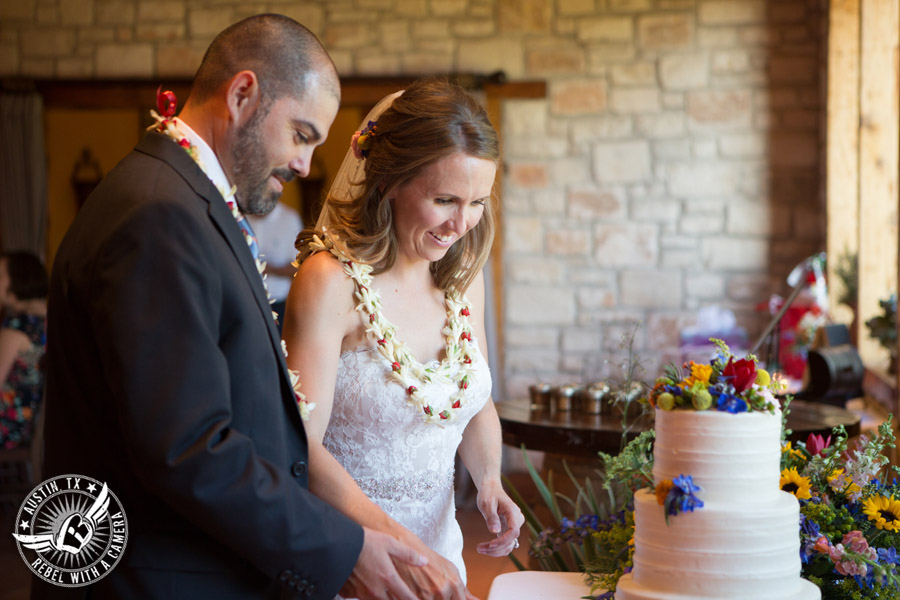 Wedding pictures at Thurman's Mansion at the Salt Lick - bride and groom cut white buttercream bride's wedding cake Sweet Treets Bakery with colorful wildflowers by Verbena Floral Design