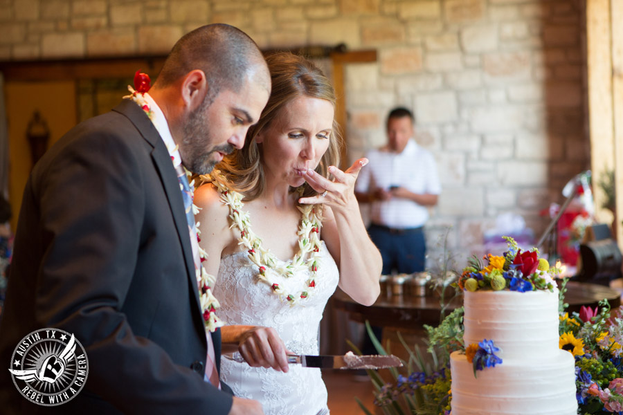 Wedding pictures at Thurman's Mansion at the Salt Lick - bride and groom cut white buttercream bride's wedding cake Sweet Treets Bakery with colorful wildflowers by Verbena Floral Design