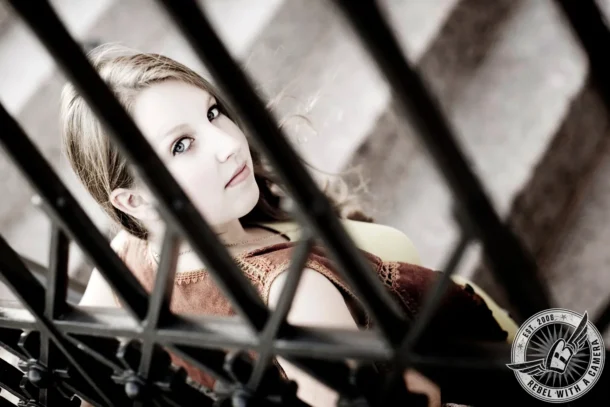 Black and white senior portrait framed through metal rails in Austin, TX.