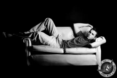 Black and white senior portrait of a young man reclining on a couch in Austin, TX.