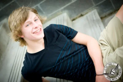 Smiling blond senior reclining in a black striped shirt in Austin, TX.