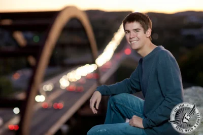 Austin senior portrait of a young man seated with blurred evening traffic behind him in Austin, TX.