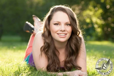 Smiling Austin senior portrait of a young woman lying in grass in Austin, TX.