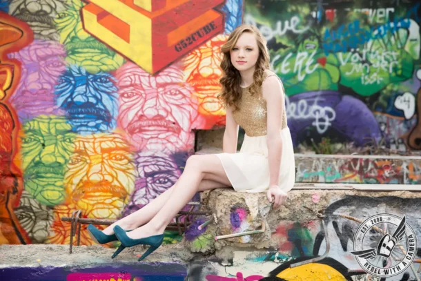 Karina Austin senior portrait seated in front of a graffiti mural in Austin, TX.