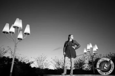 Black and white senior portrait of a woman on a platform surrounded by outdoor lamps in Austin, TX.