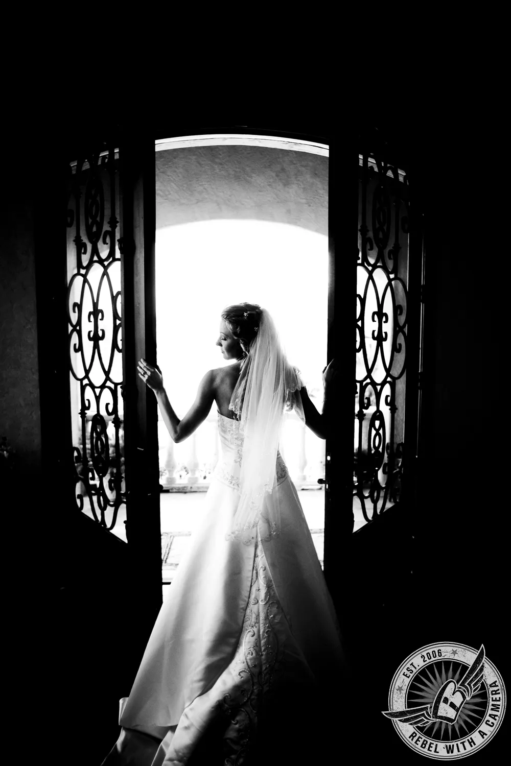 Black-and-white silhouette of a veiled bride standing in an ornate doorway in Austin, TX.