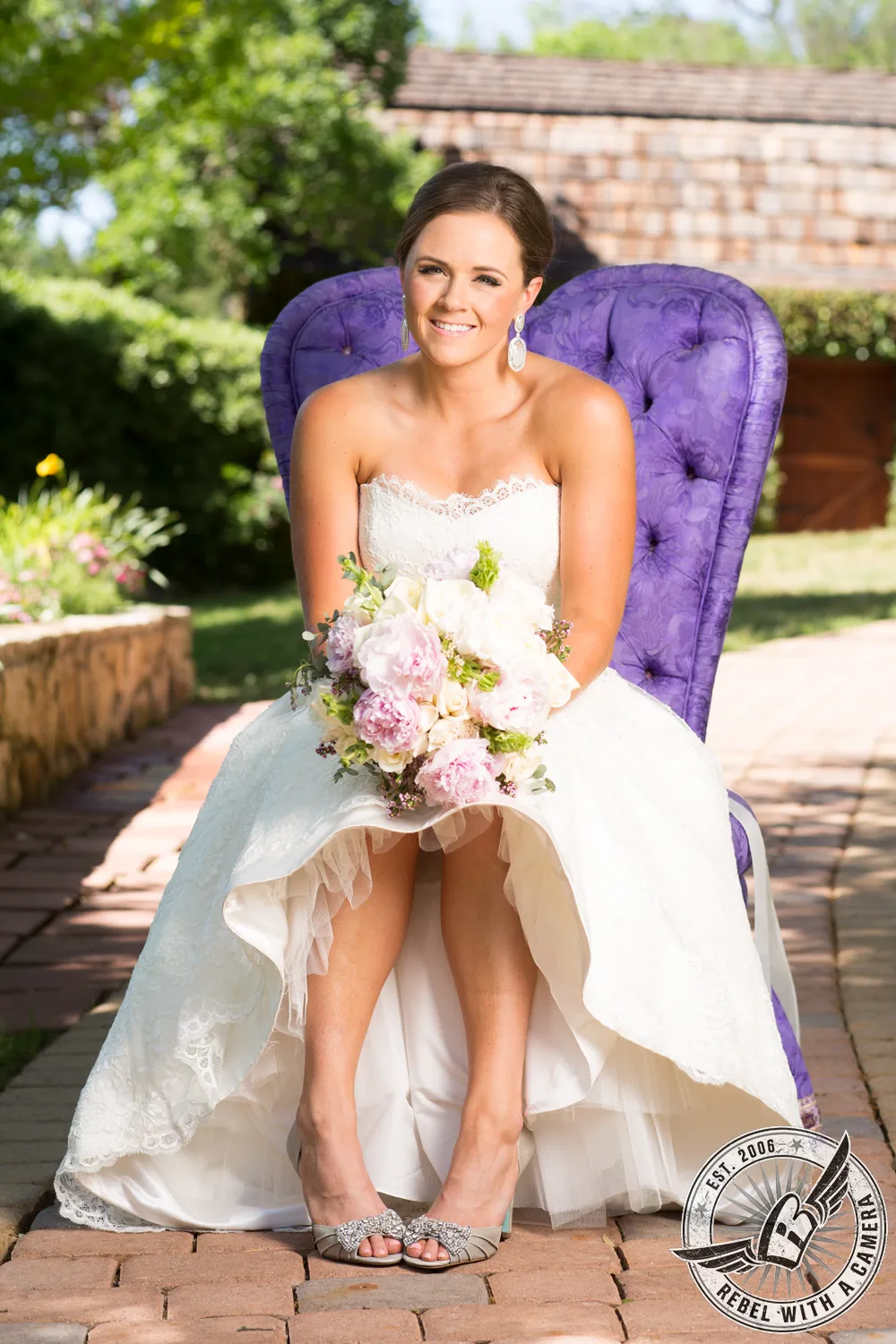 Smiling bride seated in a purple chair holding a large pastel bouquet outdoors in Austin, TX.